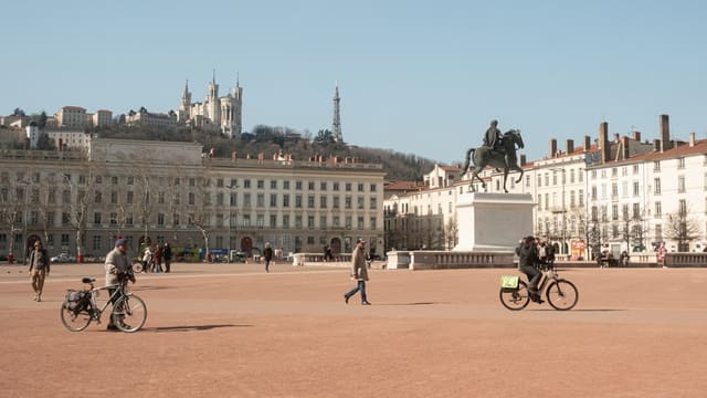 People cycling and walking in a large european city square.
