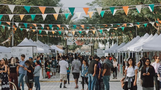 a crowd of people walking around a street next to tents