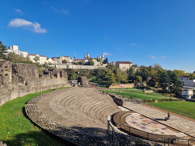 The Roman Odeon at Fourvière, Lyon, France. The white towers of the Basilique Notre-Dame de Fourvière can be seen mid-left, and the grey wall of the Lugdunum Museum below it. The Roman Theatre is out