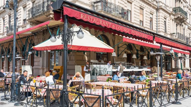 a group of people sitting at tables outside of a restaurant