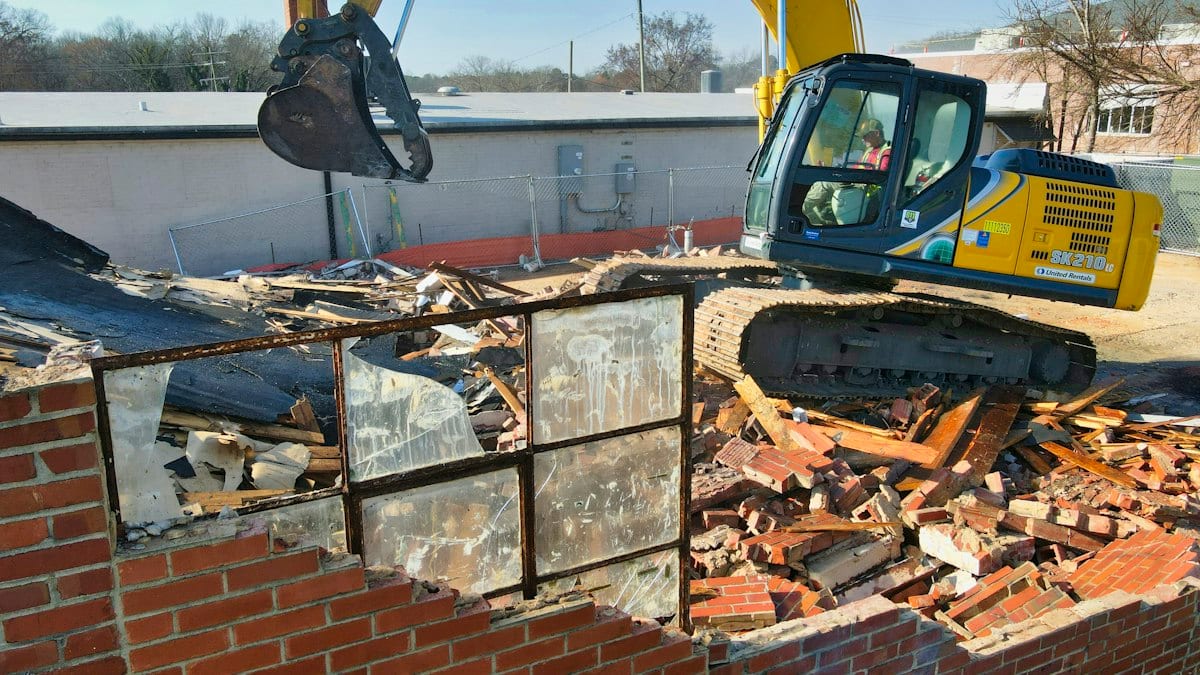 Excavatrice jaune et noire devant mur brique brun