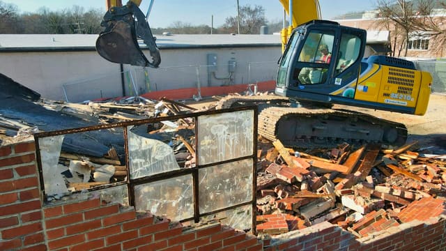 yellow and black excavator on brown brick wall during daytime