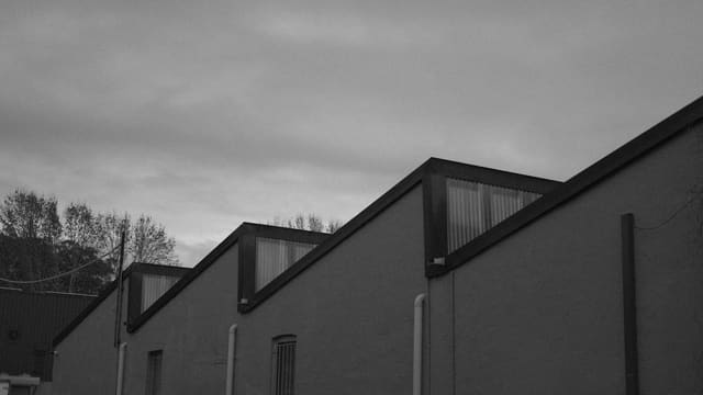 Industrial building with sawtooth roof and skylights under cloudy sky