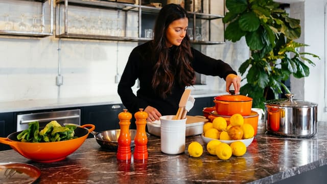 woman standing in front of fruits holding pot's lid
