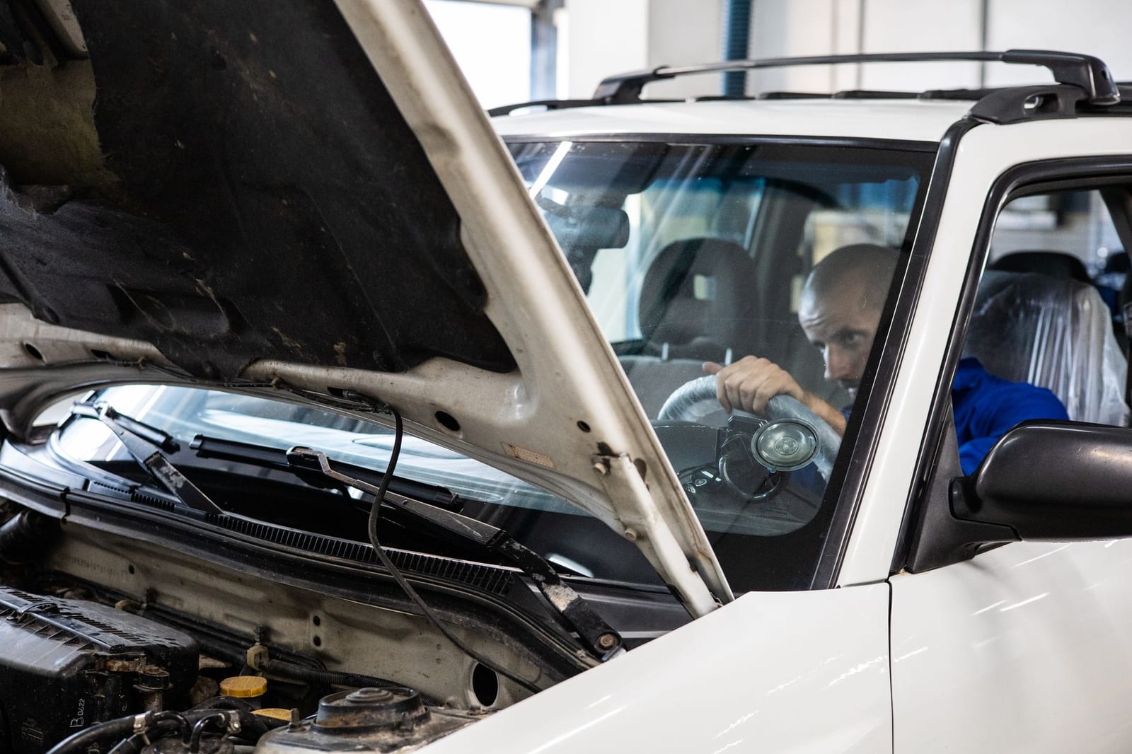 A mechanic performs a detailed inspection on a vehicle in a workshop setting.