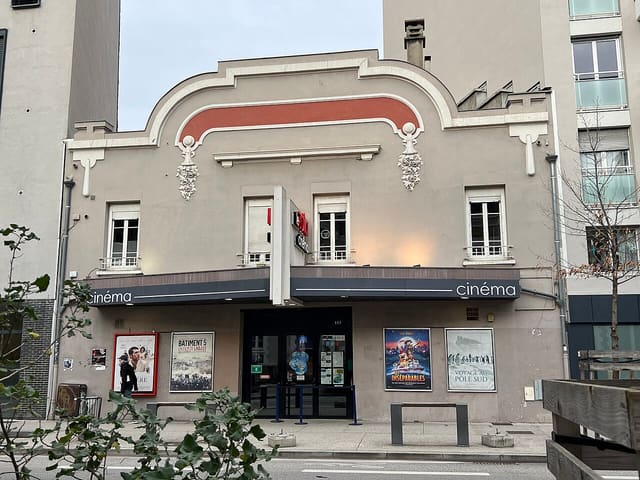 Façade du cinéma Le Zola, cours Émile-Zola à Villeurbanne, avec son fronton crème et rouge brique et ses affiches de films sous l'auvent
