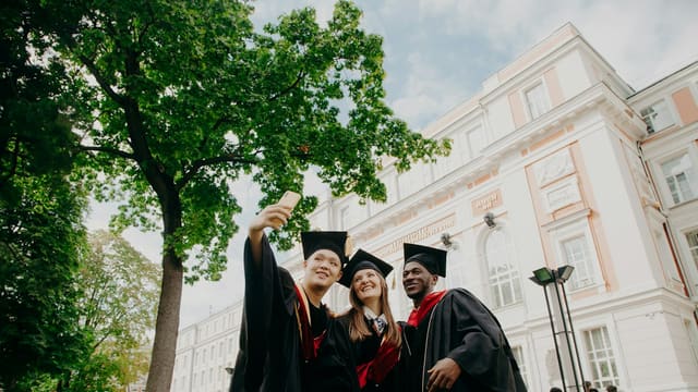 3 women in black academic dress standing near green tree during daytime