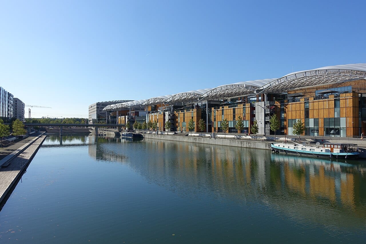 La darse de Confluence à Lyon, avec ses péniches amarrées et le Pôle de loisirs reflétés dans l'eau calme du bassin.
