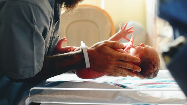 Personne en chemise grise pesant un bébé