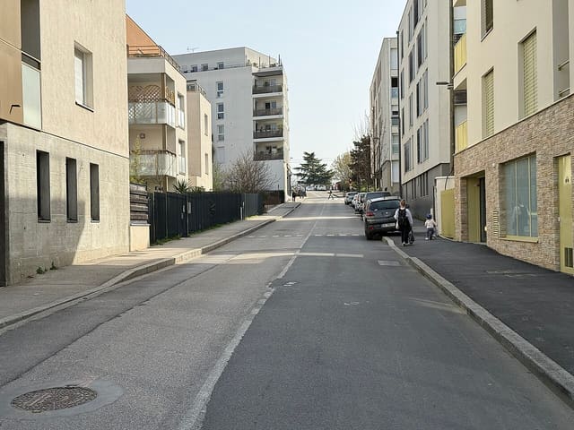 Rue de Montessuy à Caluire-et-Cuire, avec ses immeubles résidentiels et une mère accompagnant son enfant à vélo