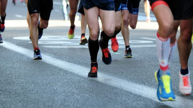 Gros plan sur les jambes et les chaussures de coureurs lors d'une course sur route