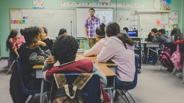 students in classroom with teacher presenting