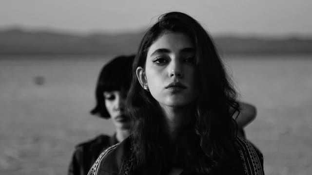 Two women gaze towards the viewer in monochrome.