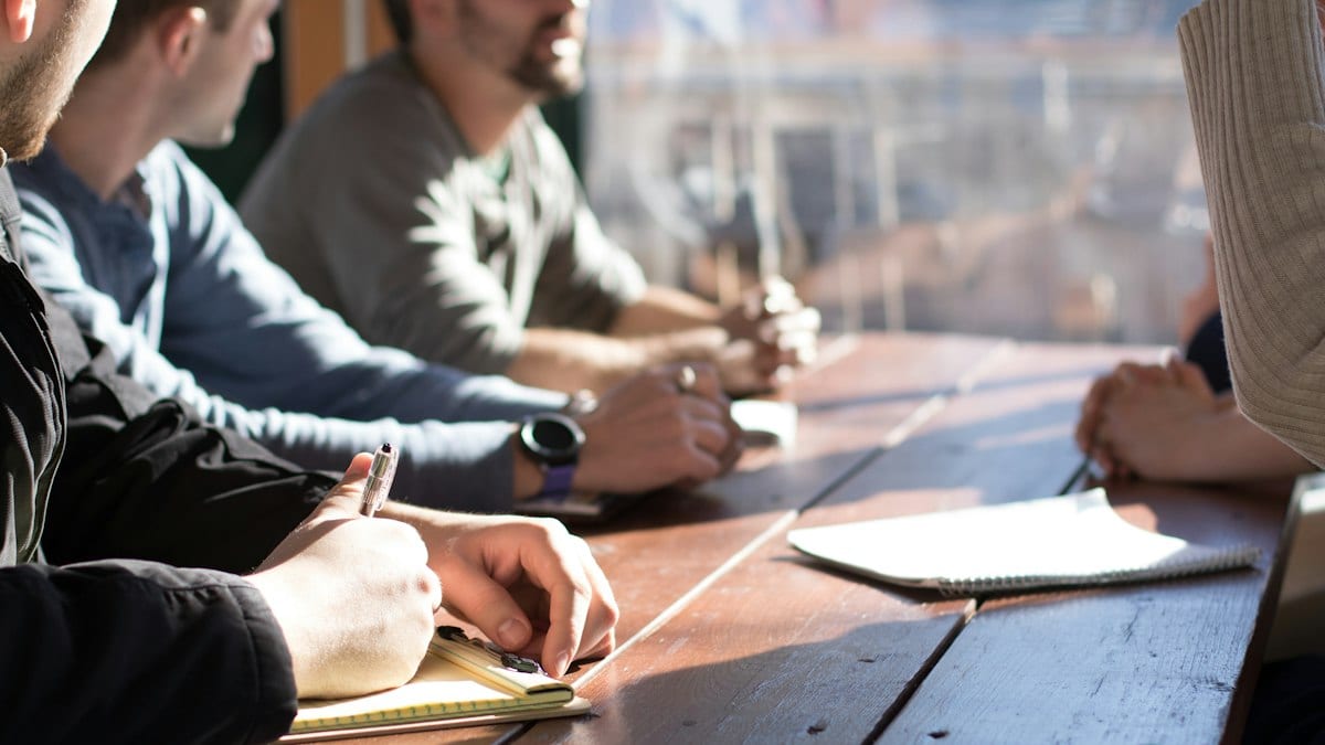 Personnes assises devant une table tenant des stylos