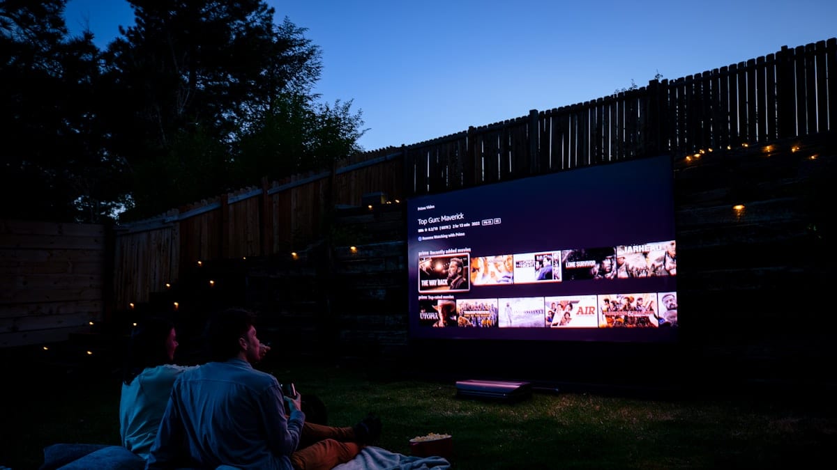 Two people sitting on a blanket watching a movie