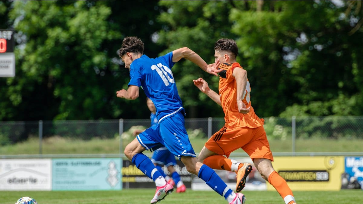 man in blue and orange jersey shirt running on green grass field during daytime