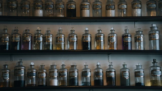 Rows of glass apothecary jars filled with colorful liquids.