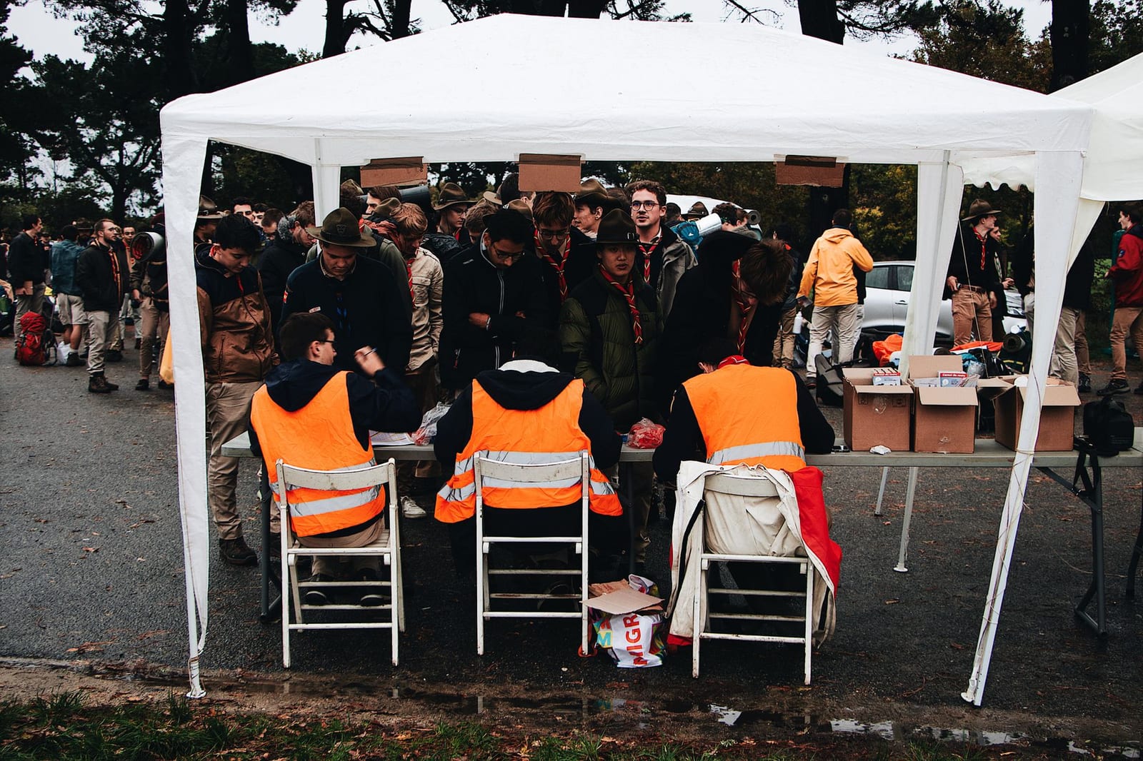 Foule à une tente d'accueil avec des bénévoles en gilets fluos