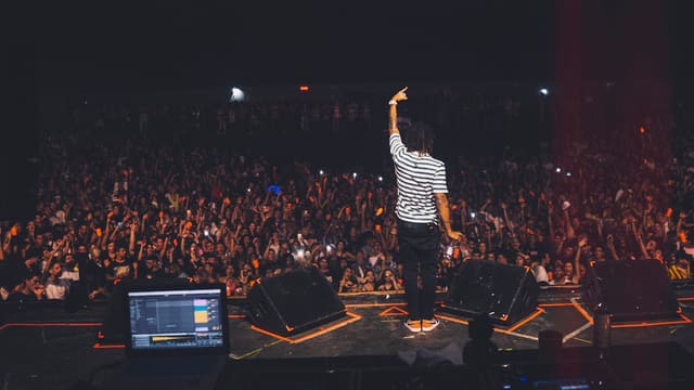 man in white and black striped shirt standing on stage