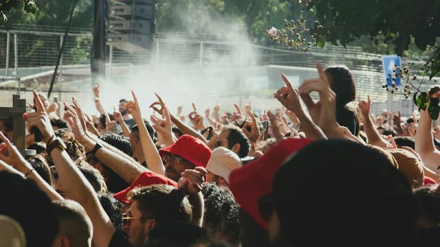 a crowd of people with their hands up in the air