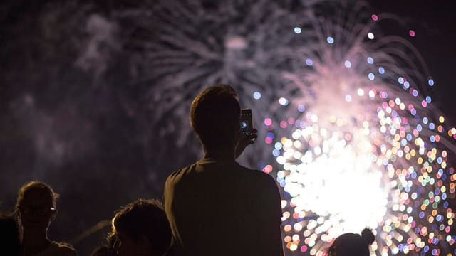 man taking picture of firecracker