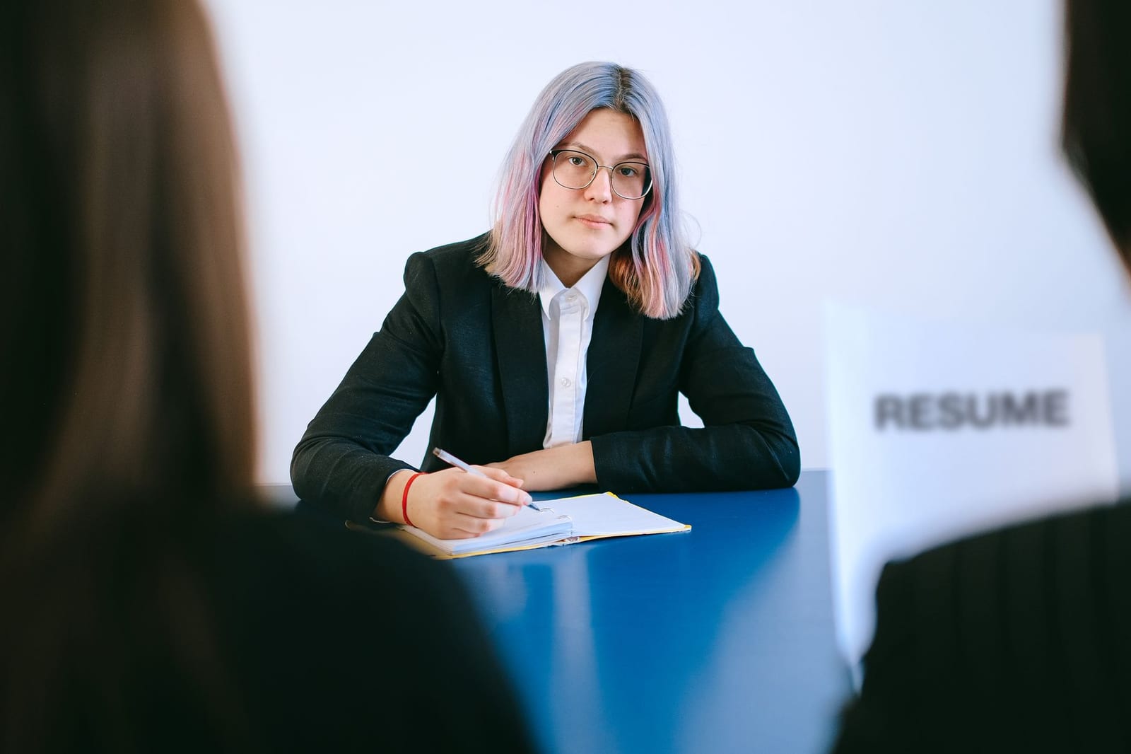 Jeune femme aux cheveux teints prenant des notes en entretien