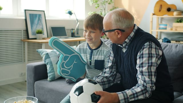 Grandfather and grandson with foam finger and soccer ball.