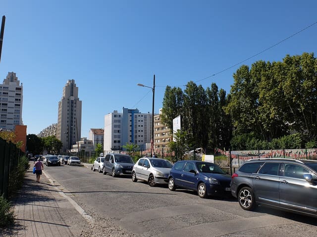 Les tours des Gratte-Ciel de Villeurbanne vues depuis une rue voisine, sous un ciel dégagé, avec des immeubles plus récents au premier plan