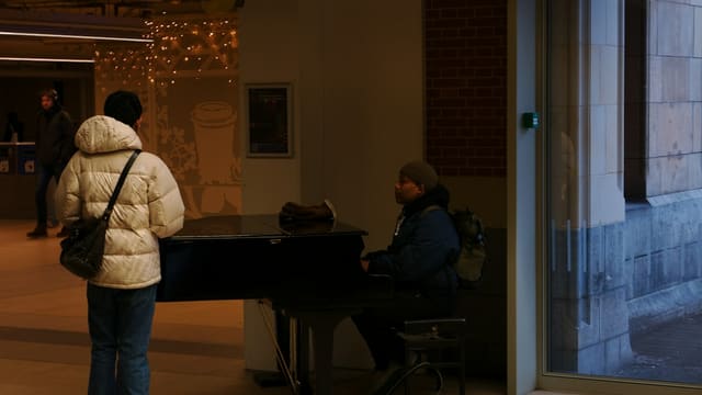 Person plays piano while another person watches