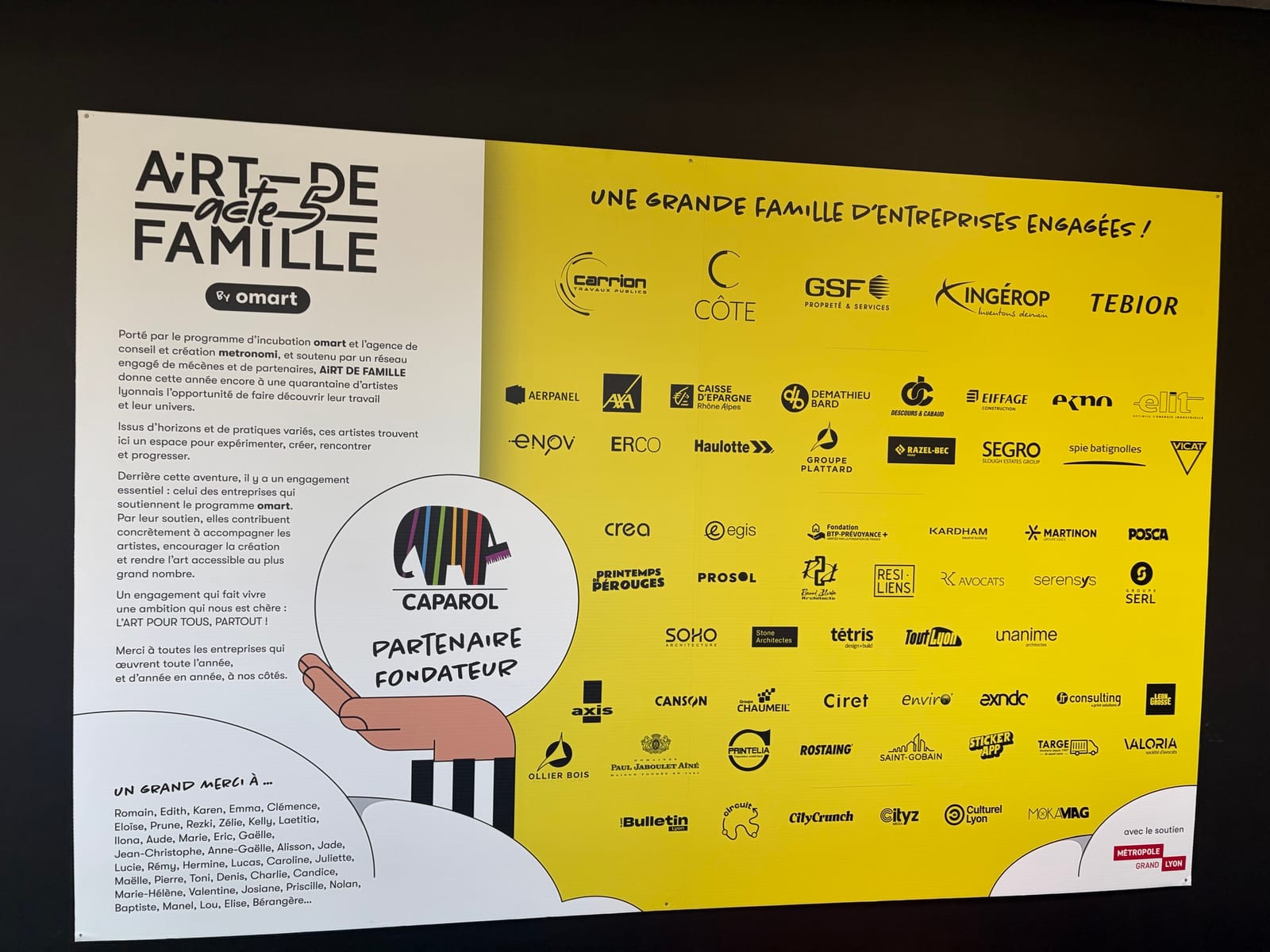 Un grand panneau d'exposition : à gauche le texte de présentation du festival sur fond blanc, à droite une soixantaine de logos d'entreprises partenaires sur fond jaune
