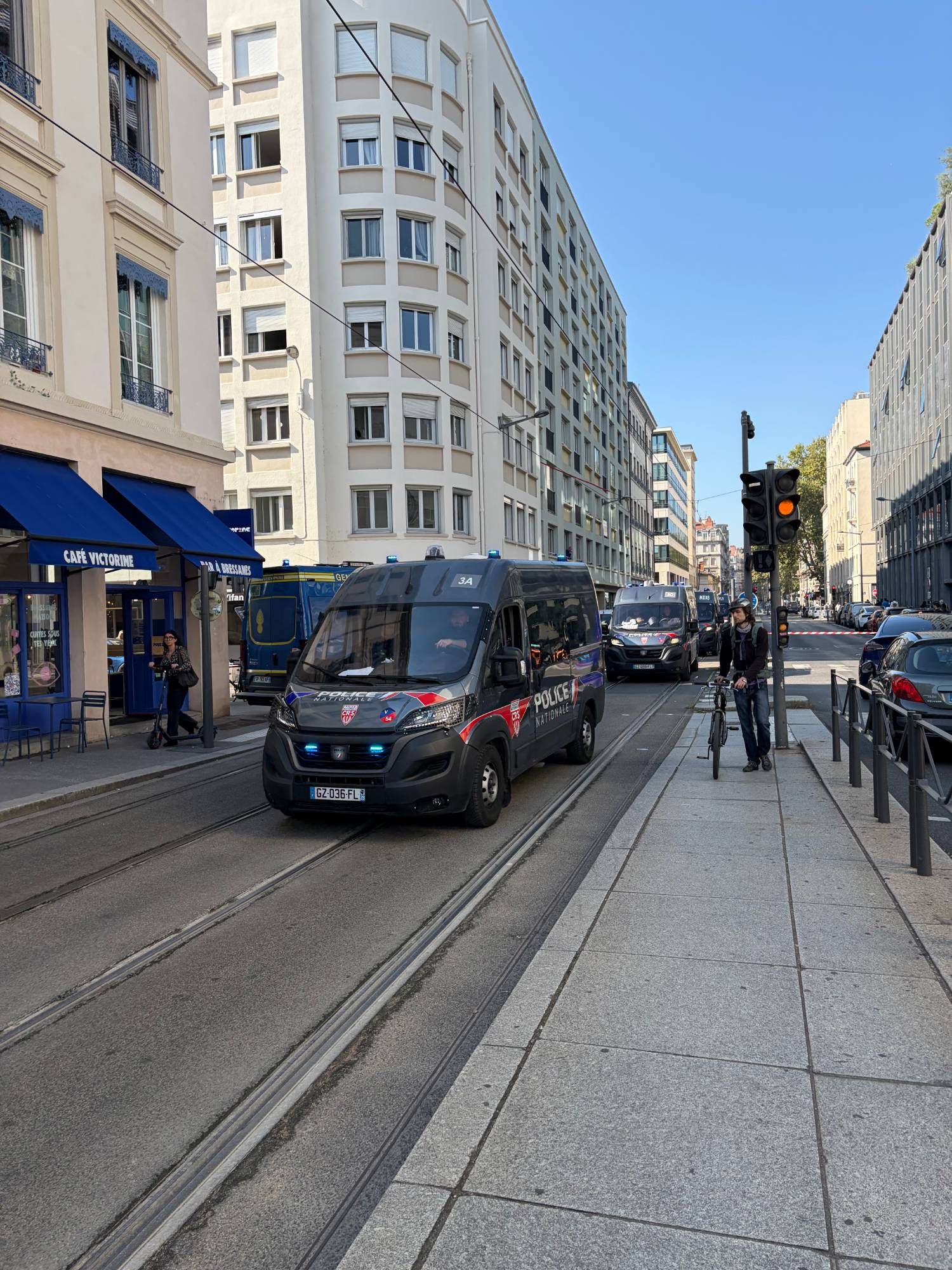 Un fourgon de police nationale CRS, suivi d'autres véhicules, dans une rue du centre de Lyon