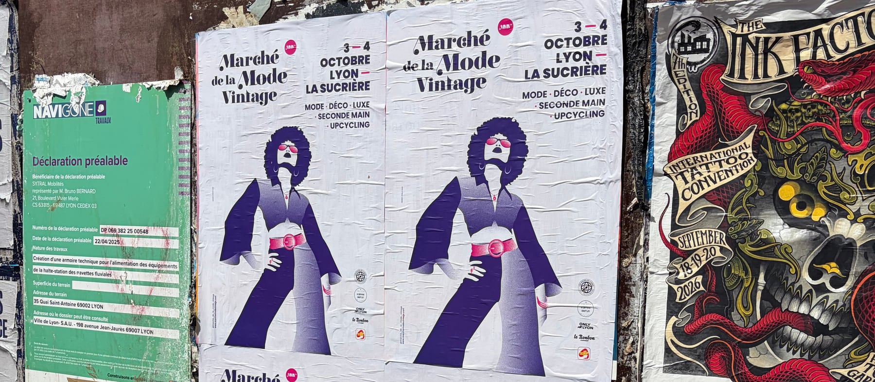 Affiches violettes du Marché de la Mode Vintage collées sur une palissade de chantier, quai Saint-Antoine à Lyon