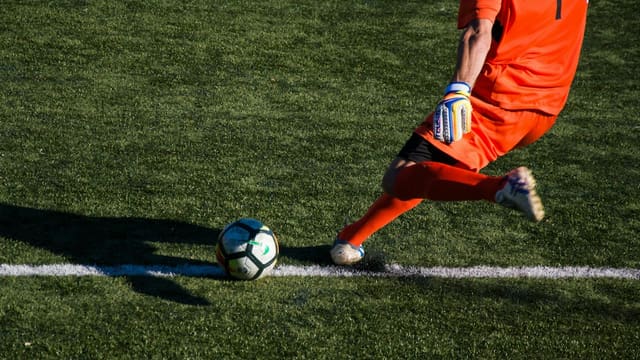 man kicking soccer ball on field