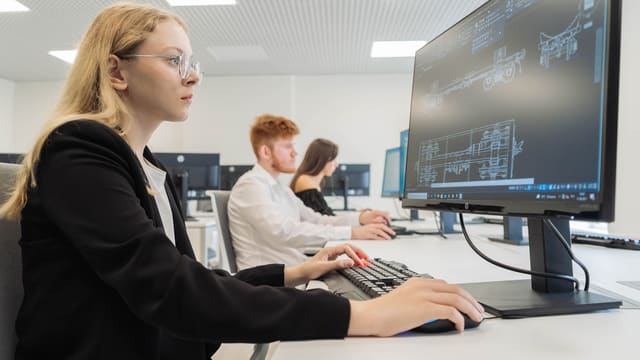 a woman sitting in front of a computer monitor