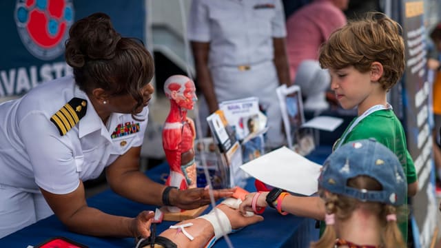 Naval officer demonstrates medical training to curious children