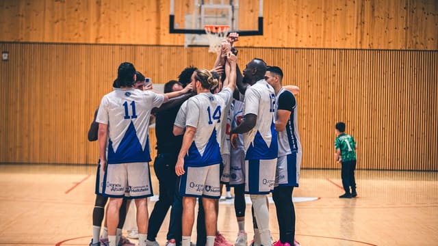 Basketball team huddles together on court