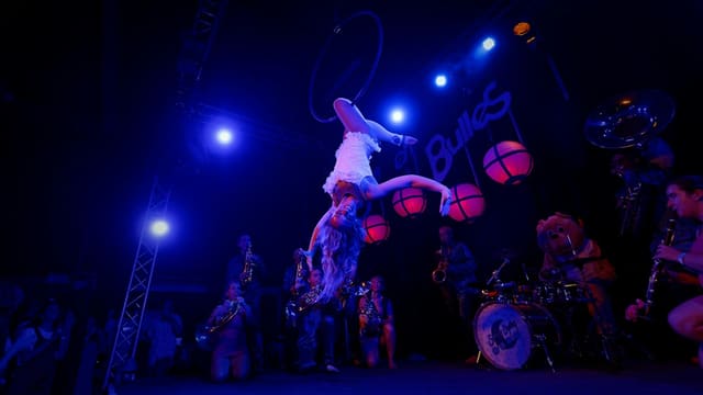 Acrobats performing on a dimly lit stage with blue lights.