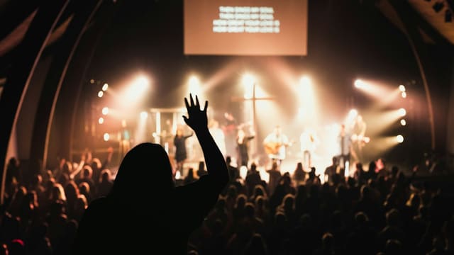 Spectateurs écoutant groupe musical sous projecteurs.