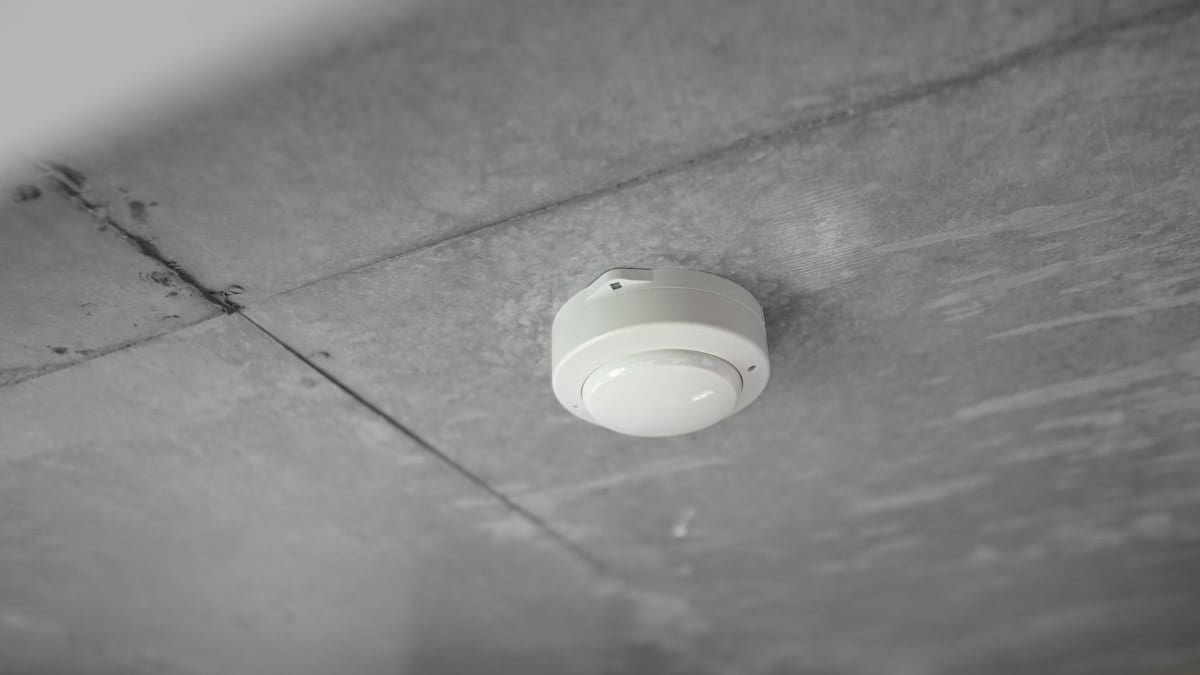Détecteur blanc fixé au plafond de béton gris d'une pièce
