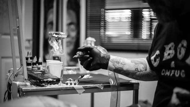 a man with tattoos on his arm holding a cigarette