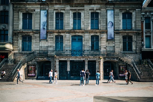 Théâtre du Nord's historic facade in Lille, France, with visitors exploring the urban landscape.