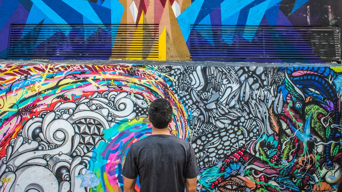 Homme admirant fresque murale colorée.
