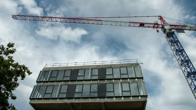 a crane is standing next to a tall building
