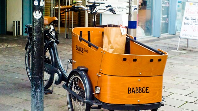 a bike with a basket attached to it parked next to a pole