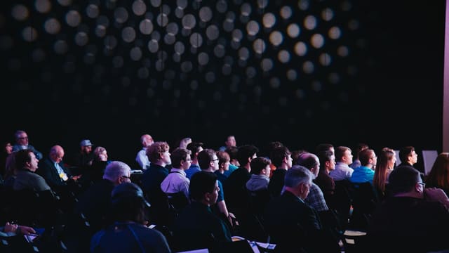 crowd of people sitting on chairs inside room