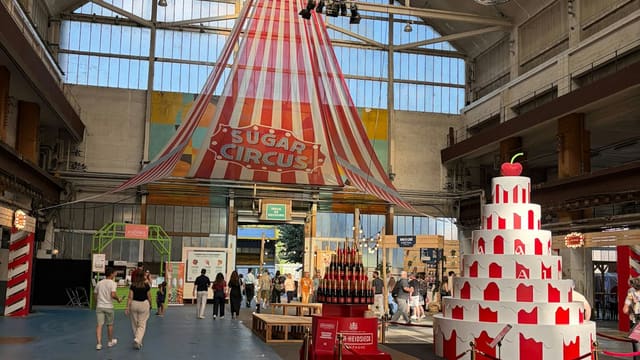 Grande halle des Grandes Locos avec un chapiteau rayé et une pièce montée géante rouge et blanc, pour les dix ans du Lyon Street Food Festival