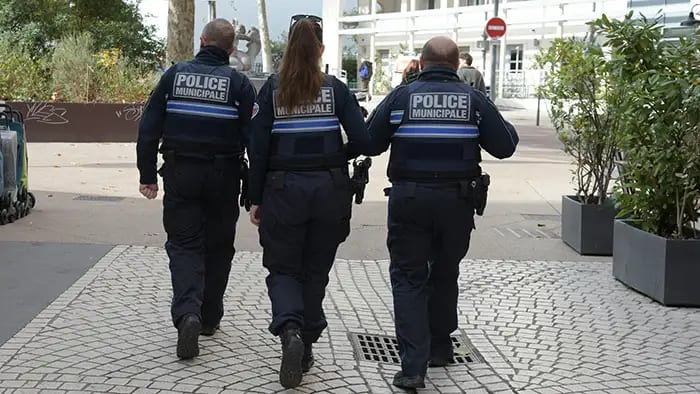 Trois policiers municipaux de Lyon en patrouille à pied dans une rue pavée du centre-ville