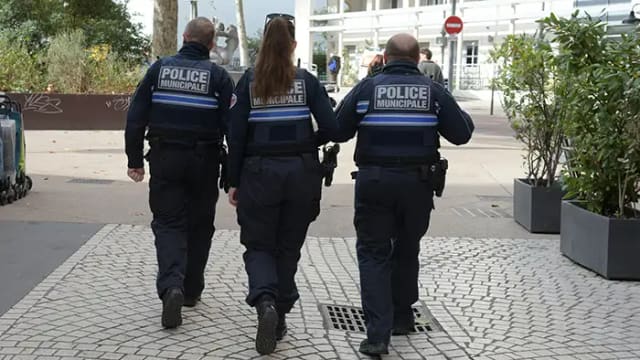 Trois policiers municipaux de Lyon en patrouille à pied dans une rue pavée du centre-ville
