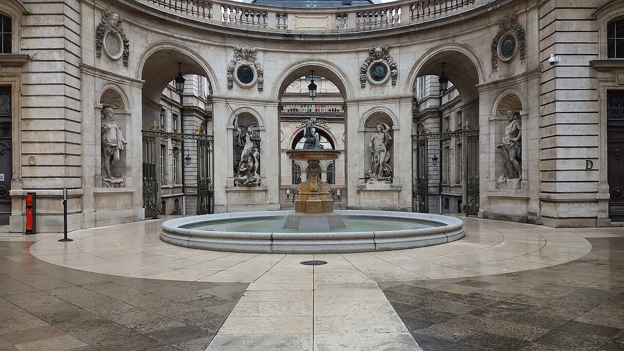 Cour intérieure de l'hôtel de ville de Lyon avec sa fontaine centrale et ses statues sous les arcades