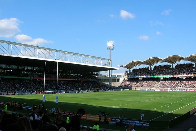 Vue de la pelouse et des tribunes du stade de Gerland, domicile du LOU Rugby, lors d'un match de rugby devant un public nombreux.